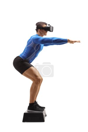 Photo for Full length profile shot of a man exercising with a vr headset on top of a step aerobic platform isolated on white background - Royalty Free Image