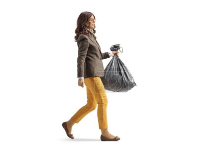 Téléchargez les photos : Full length profile shot of a young woman in formal clothes carrying a plastic waste bag isolated on white background - en image libre de droit