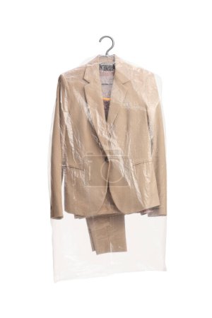 Téléchargez les photos : Beige female suit on a hanger with a plastic dry cleaning bag isolated on a white background - en image libre de droit