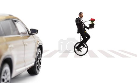 Téléchargez les photos : Homme en monocycle sur un passage piétonnier et effectuant un tour de magie isolé sur fond blanc - en image libre de droit