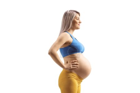 Téléchargez les photos : Profile shot of a pregnant woman in a blue crop top isolated on white background - en image libre de droit