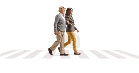 Photo for Young woman holding an elderly man under arm and walking on a pedestiran crossing isolated on white background - Royalty Free Image