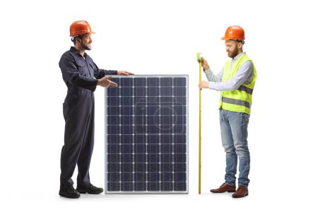 Foto de Un ingeniero y un trabajador de pie con un panel solar aislado sobre fondo blanco - Imagen libre de derechos
