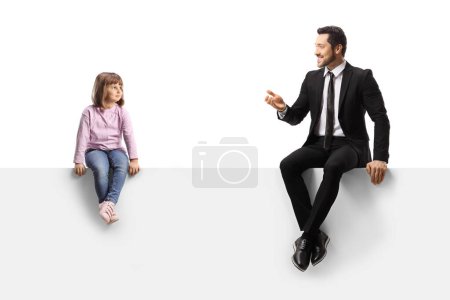 Téléchargez les photos : Child sitting on a blank panel and listening to a businessman talking isolated on white background - en image libre de droit