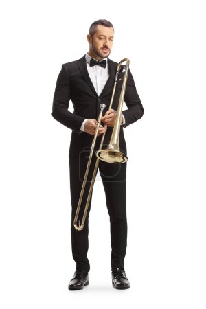 Photo for Full length portrait of a male musician holding a trombone and looking down isolated on white background - Royalty Free Image