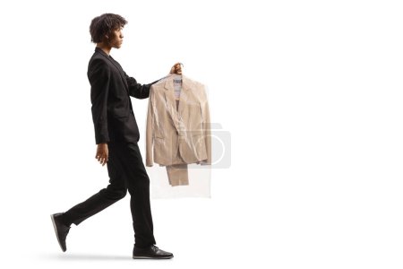 Photo for Full length profile shot of an african american man taking suit from dry cleaners isolated on a white background - Royalty Free Image