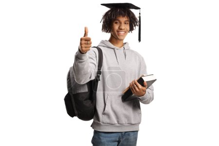 Photo for African american male student with a graduation hat gesturing thumbs up and holding books isolated on white background - Royalty Free Image