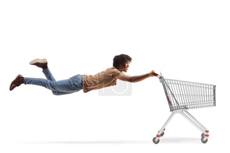 Photo for African american guy flying and holding a shopping cart isolated on white background - Royalty Free Image