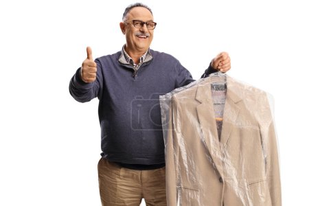 Photo for Mature man collecting suit from dry cleaners and gesturing thumbs up isolated on a white backgroun - Royalty Free Image