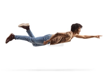 Foto de Largura completa de un hombre afroamericano volando y señalando aislado sobre fondo blanco - Imagen libre de derechos