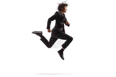 Téléchargez les photos : Full length profile shot of an african american man in a black suit jumping isolated on white background - en image libre de droit