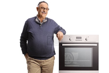 Photo for Smiling mature man leaning on an oven isolated on white background - Royalty Free Image
