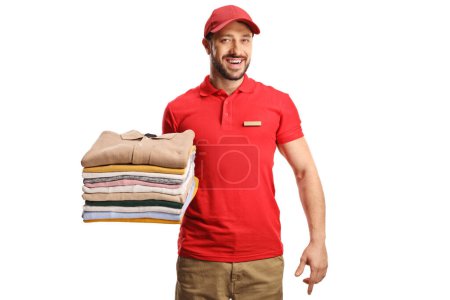 Männlicher Arbeiter hält einen Stapel zusammengefalteter Kleidung isoliert auf einem weißen Hintergrund