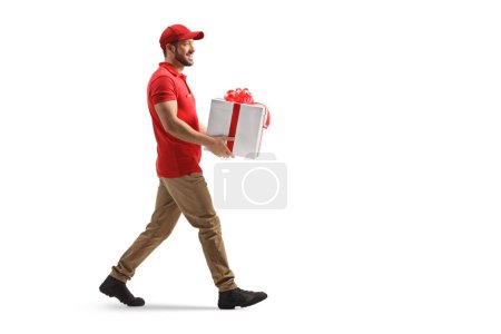 Téléchargez les photos : Full length profile shot of a delivery worker carrying a present box isolated on white background - en image libre de droit