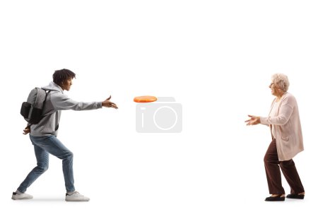 Téléchargez les photos : Full length profile shot of a young african american man throwing a flying disc with an elderly woman isolated on white background - en image libre de droit