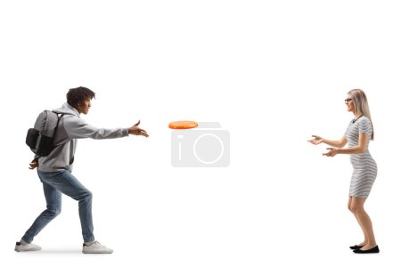 Photo for Full length profile shot of a young african american man throwing a flying disc with a young caucasian woman isolated on white background - Royalty Free Image