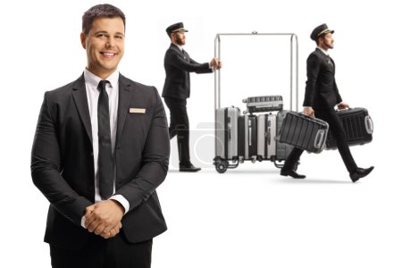 Téléchargez les photos : Hotel manager and bellboys carrying suitcases and pushing a luggage cart isolated on white backgroun - en image libre de droit