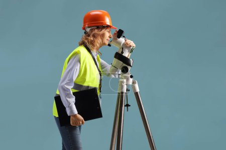 Téléchargez les photos : Profile shot of a female geodetic surveyor working with a measuring device isolated on white background - en image libre de droit