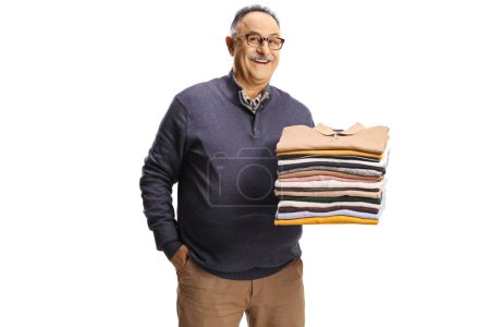 Photo for Cheerful mature man holding a pile of folded clothes and smiling at camera isolated on a white backgroun - Royalty Free Image