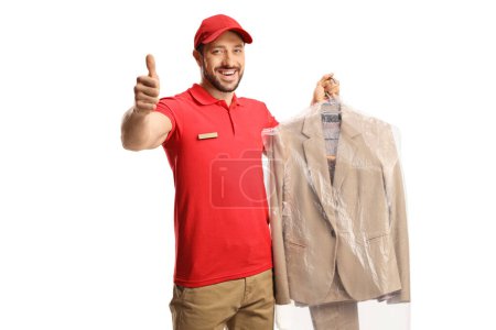 Photo for Worker holding a suit on a hanger with a plastic cover and gesturing thumbs up isolated on a white backgroun - Royalty Free Image