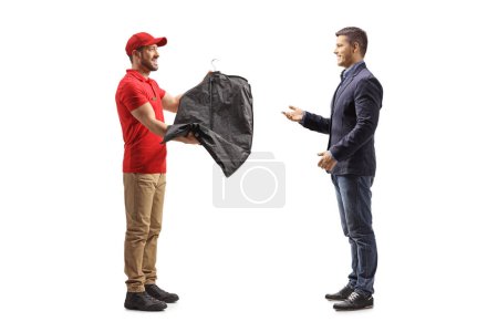 Foto de Trabajador entregando un traje en una percha con una cubierta a un cliente masculino aislado en un fondo blanco - Imagen libre de derechos