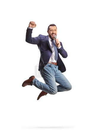 Téléchargez les photos : Animateur de télévision masculin excité avec un micro sautant isolé sur fond blanc - en image libre de droit