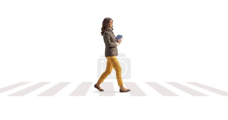 Téléchargez les photos : Jeune femme portant des livres et traversant la rue isolée sur fond blanc - en image libre de droit
