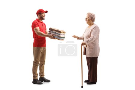 Foto de Trabajadora de lavandería entregando una pila de ropa doblada a una anciana aislada sobre un fondo blanco - Imagen libre de derechos