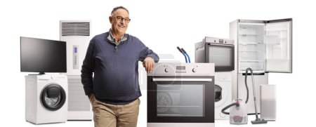 Foto de Hombre maduro sonriente con muchos electrodomésticos apoyados en un horno aislado sobre fondo blanco - Imagen libre de derechos