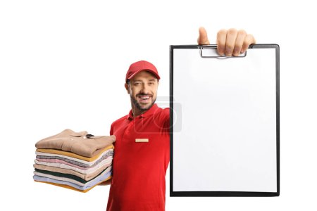 Photo for Laundry worker holding a pile of folded clothes and showing a blank document isolated on a white backgroun - Royalty Free Image