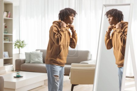 Téléchargez les photos : Jeune homme afro-américain debout devant un miroir à la maison - en image libre de droit