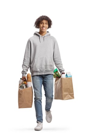 Photo for Full length portrait of a smiling young african american man carrying grocery bags isolated on white background - Royalty Free Image