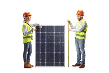 Foto de Ingenieros masculinos y femeninos midiendo un panel solar aislado sobre fondo blanco - Imagen libre de derechos