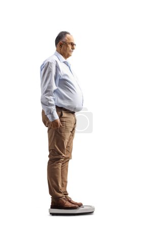 Téléchargez les photos : Plan de profil complet d'un homme mature debout sur une échelle de poids isolé sur fond blanc - en image libre de droit