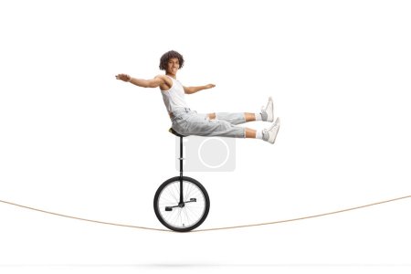 Acróbata afroamericana sentada sobre un monociclo sobre una cuerda aislada sobre fondo blanco