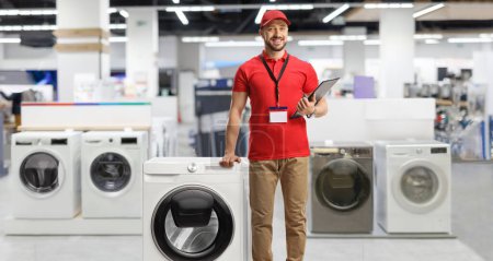 Photo for Appliance sales associate leaning on a washing machine inside a shop - Royalty Free Image