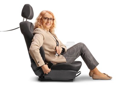 Foto de Mujer madura sentada en un asiento de coche y poniéndose un cinturón de seguridad aislado sobre fondo blanco - Imagen libre de derechos