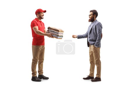 Foto de Hombre entregando pila de ropa de limpieza en seco a un cliente masculino aislado en un fondo blanco - Imagen libre de derechos