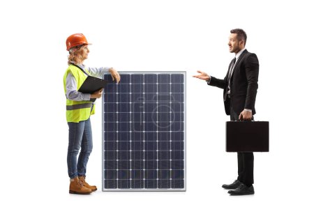 Téléchargez les photos : Homme d'affaires parlant à une ingénieure avec un panneau solaire isolé sur fond blanc - en image libre de droit