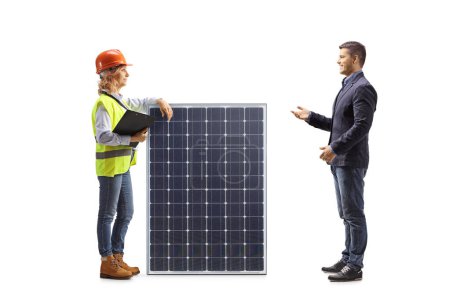 Téléchargez les photos : Homme occasionnel parlant à une ingénieure avec un panneau solaire isolé sur fond blanc - en image libre de droit