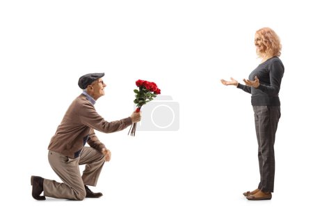 Photo for Senior man kneeling and giving a red roses to a woman isolated on white background - Royalty Free Image