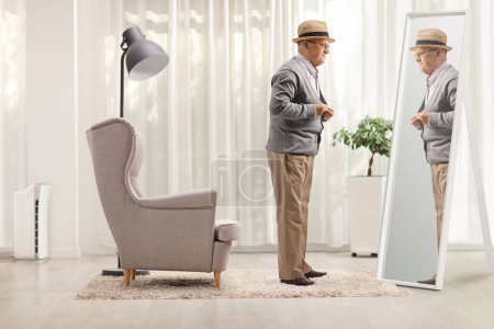 Téléchargez les photos : Plan complet d'un gentleman âgé s'habillant devant un miroir à la maison - en image libre de droit