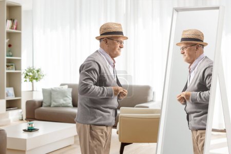 Téléchargez les photos : Homme âgé s'habiller devant un miroir à la maison - en image libre de droit