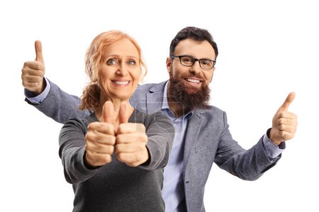 Téléchargez les photos : Homme barbu geste pouces levés et debout derrière une femme mature gaie isolée sur fond blanc - en image libre de droit