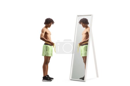 Photo for Young african american athlete measuring waist in front of a mirror isolated on white backgroun - Royalty Free Image
