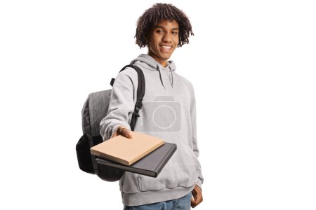 Téléchargez les photos : Étudiant afro-américain avec un sac à dos donnant des livres et souriant isolé sur fond blanc - en image libre de droit