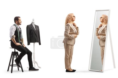 Photo for Woman trying on a clothes in front of mirror at the tailors shop isolated on white background - Royalty Free Image