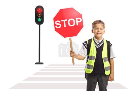 Photo for Boy with a safety vest and a stop traffic sign standing at a pedestrian crossing with a traffic light - Royalty Free Image