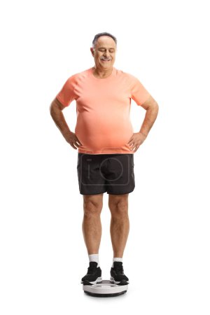 Photo for Mature man in sportswear standing on a weight scale and looking down isolated on white background - Royalty Free Image