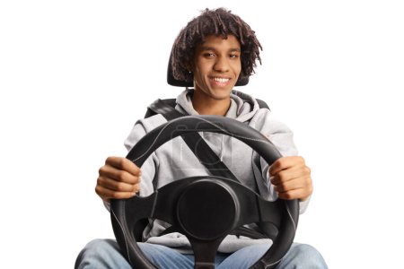 Foto de Conductor masculino joven afroamericano sentado en un asiento de coche y sosteniendo un volante aislado sobre fondo blanco - Imagen libre de derechos